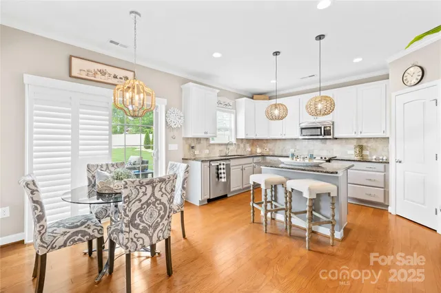 a kitchen with stainless steel appliances granite countertop a stove a refrigerator a kitchen island with a dining table and chairs