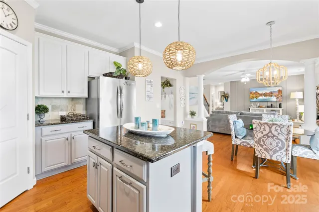 a kitchen with stainless steel appliances granite countertop a stove a refrigerator a oven a dining table and chairs with the bookshelf