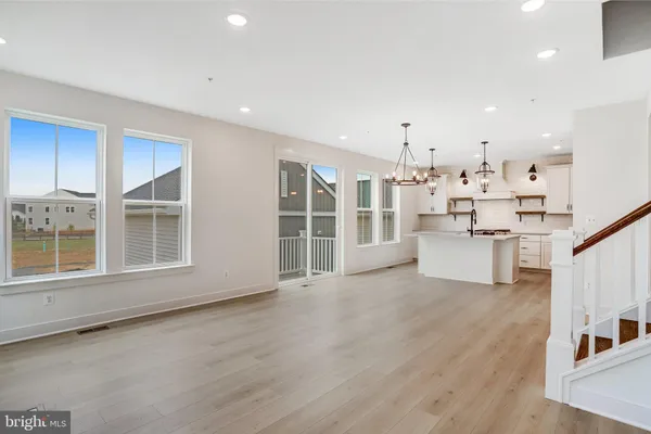 a kitchen with stainless steel appliances granite countertop a sink a stove a refrigerator and island with wooden floor