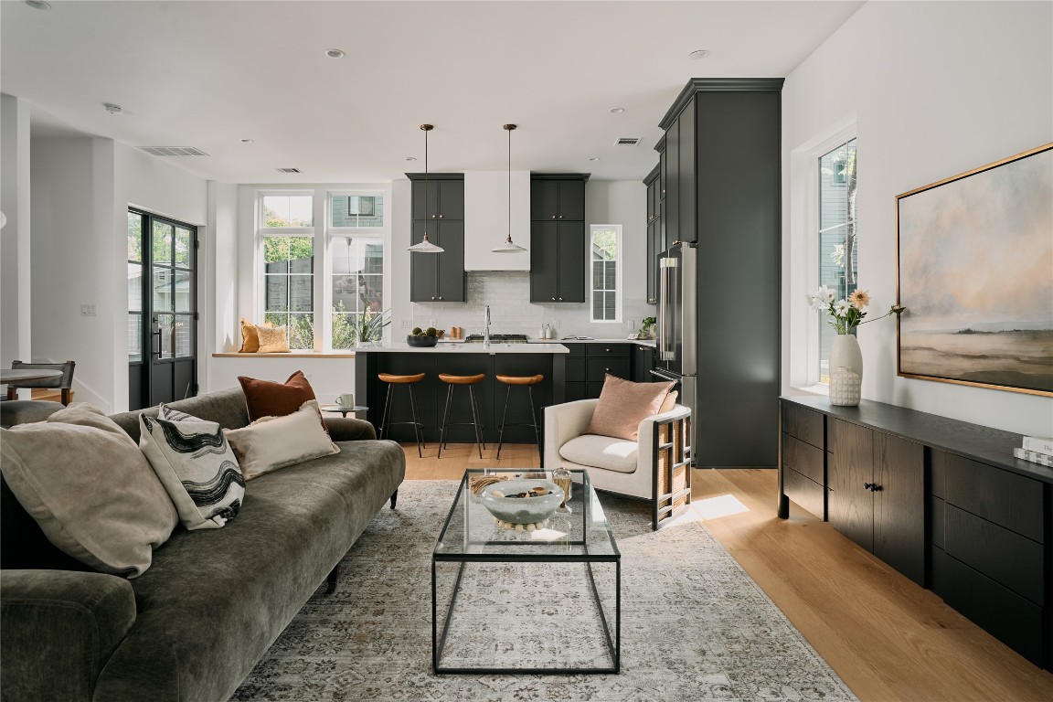 a living room with furniture a large window and wood floor