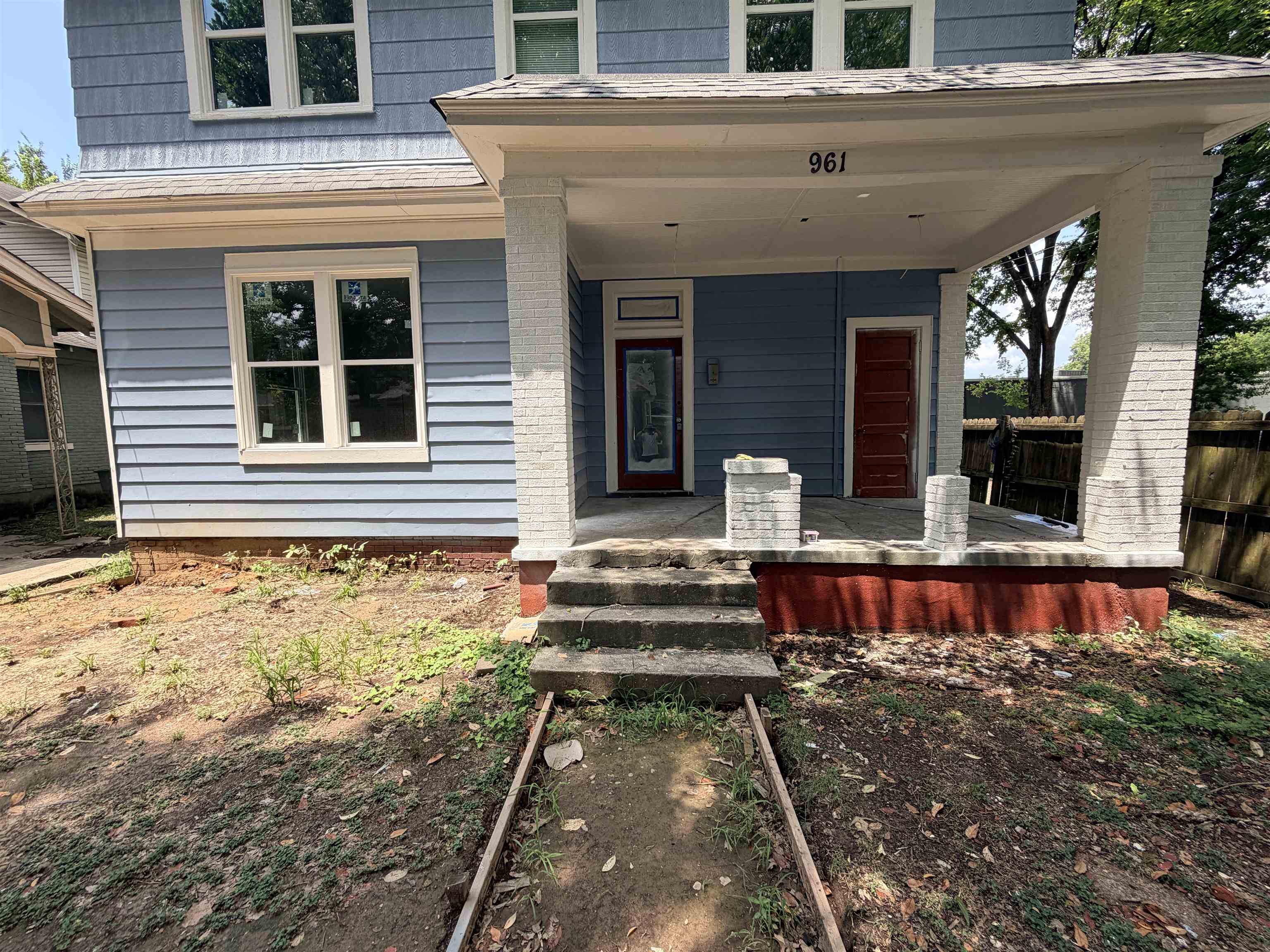 961 Meda Street Memphis, TN 38104 - Photo 4 of 27 Two-story residence featuring light blue siding, a covered front porch with white columns, and multi-pane windows