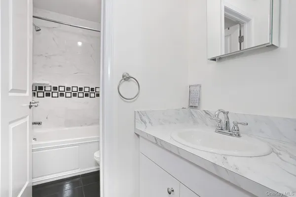 a bathroom with a granite countertop sink a mirror and shower