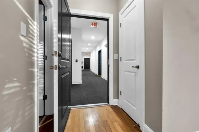 a view of a hallway with wooden floor and a bathroom