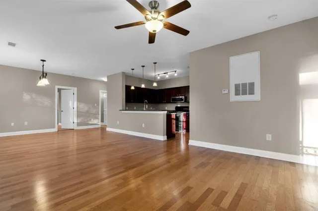 a view of an empty room with kitchen and window