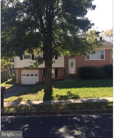 a view of a yard in front of a house with a large tree