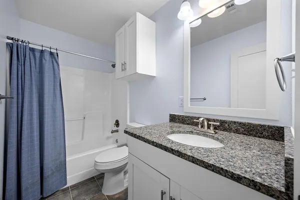 a bathroom with a granite countertop sink toilet and shower