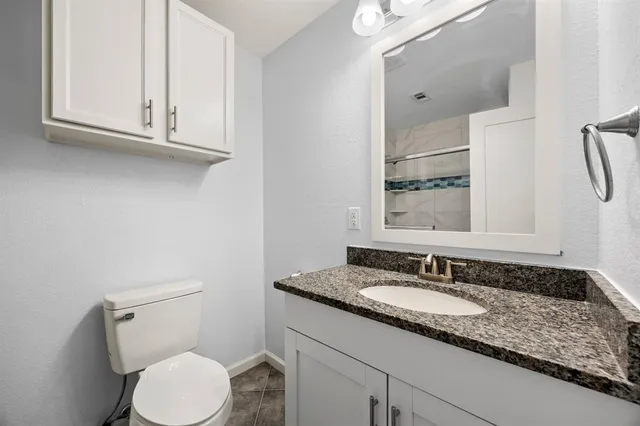 a bathroom with a granite countertop toilet sink and mirror