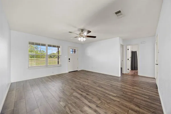 a view of an empty room with a window and wooden floor
