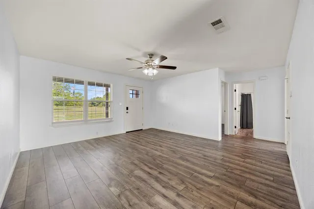 a view of an empty room with a window and wooden floor