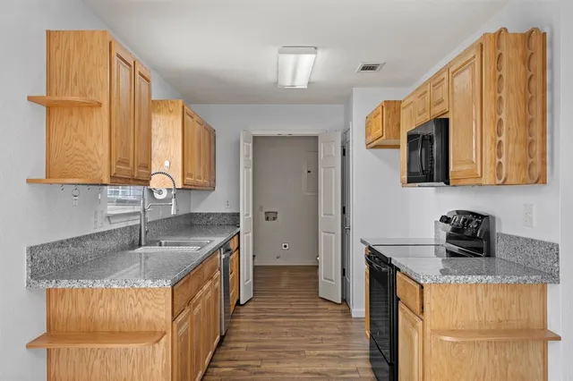 a kitchen with stainless steel appliances granite countertop a sink a stove and a refrigerator
