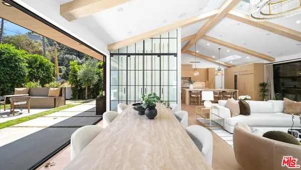 a living room with furniture large windows and wooden floor