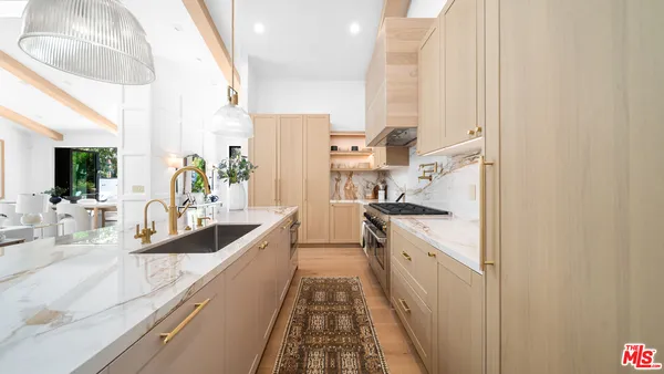 a view of a kitchen with kitchen island a large window a sink and stainless steel appliances