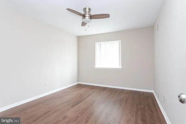 an empty room with wooden floor fan and windows