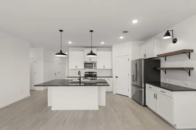 a kitchen with stainless steel appliances granite countertop a sink a stove and a refrigerator