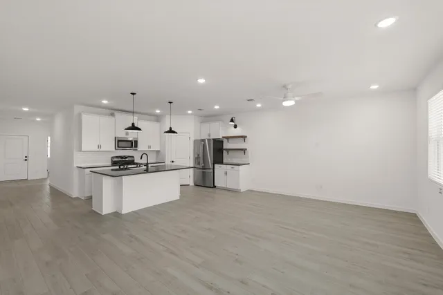 a large kitchen with stainless steel appliances kitchen island a large counter top and wooden floors