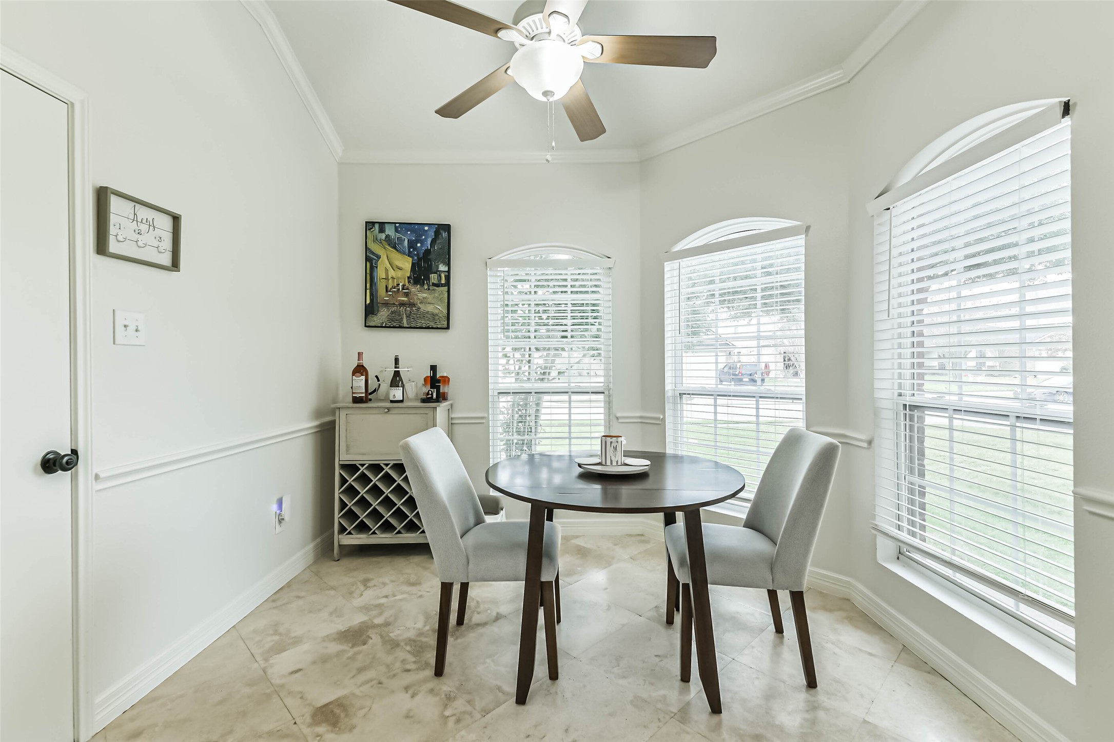 22538 Goss Spring Court Spring, TX 77373 - Photo 13 of 36 Bright dining nook with large windows, a ceiling fan, and neutral tones. Features a round table, modern chairs, and a small wine rack.