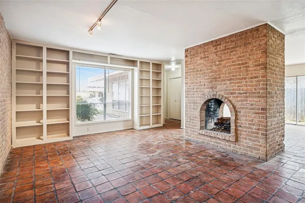 a view of an empty room with a fireplace and a window