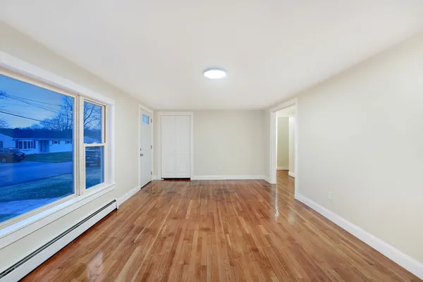 a view of an empty room and window with wooden floor