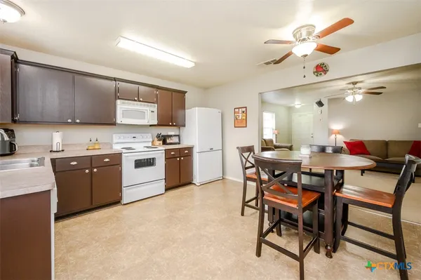 a kitchen with a table chairs a sink dishwasher stove and cabinets