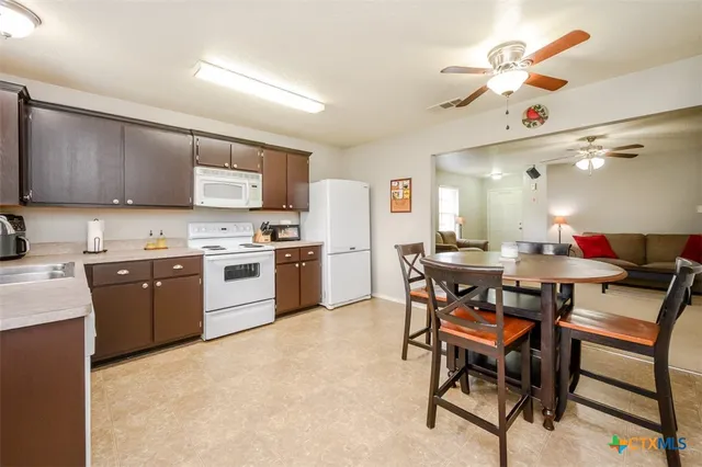 a kitchen with a table chairs a sink dishwasher stove and cabinets