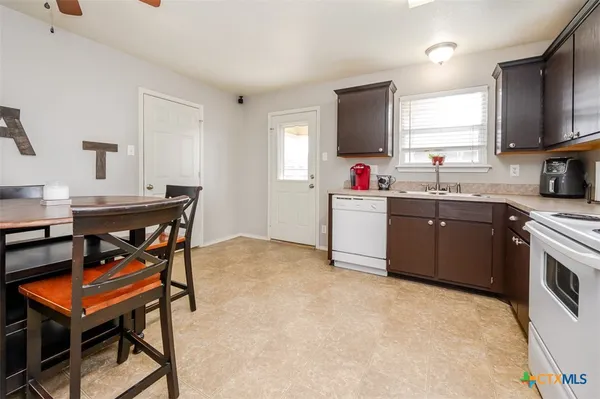 a kitchen that has a sink a stove counter top space and a window in it