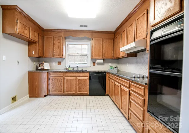 a kitchen with stainless steel appliances granite countertop a stove a sink dishwasher and a refrigerator with wooden cabinets