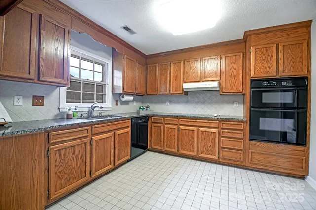 a kitchen with stainless steel appliances granite countertop wooden cabinets a sink and a window