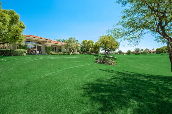 a view of a house with a yard plants and palm trees