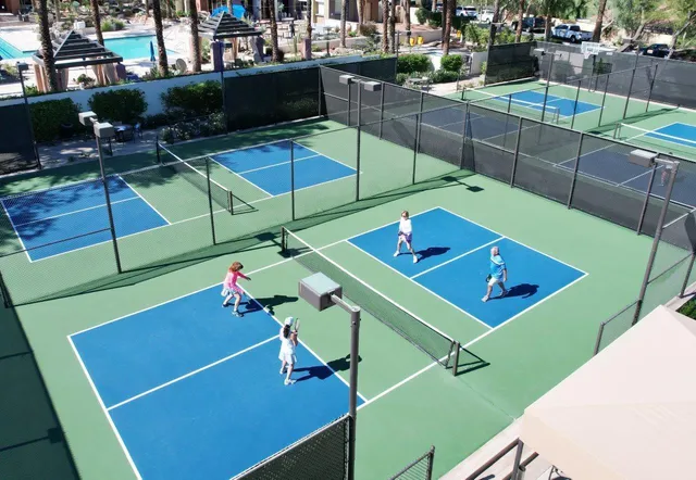a view of a tennis ground with large trees