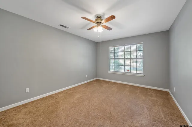an empty room with window and ceiling fan