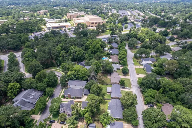 an aerial view of residential houses with outdoor space and trees