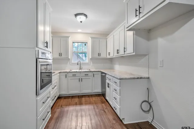 a kitchen with granite countertop a sink cabinets stainless steel appliances and a window