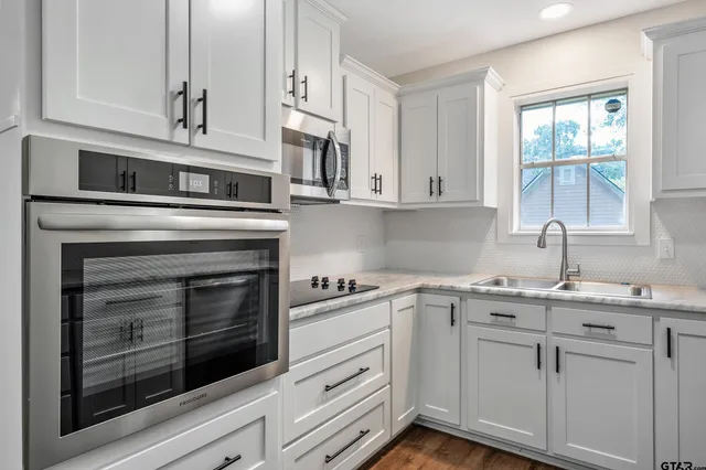 a kitchen with white cabinets and appliances
