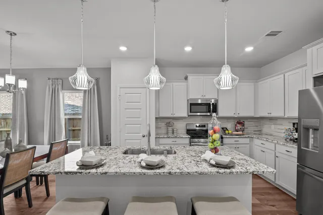 a kitchen with kitchen island granite countertop a sink cabinets and stainless steel appliances