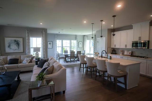 a kitchen with kitchen island granite countertop a sink a stove a dining table and chairs