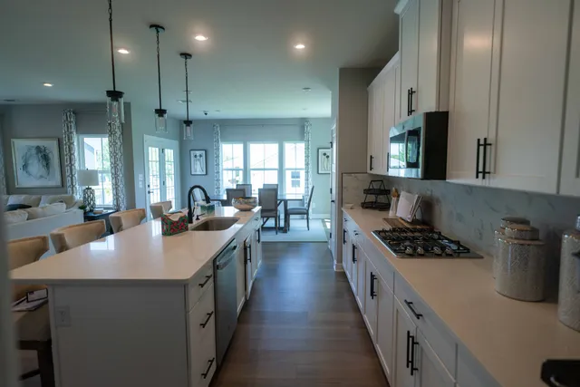 a large kitchen with cabinets chairs and wooden floor