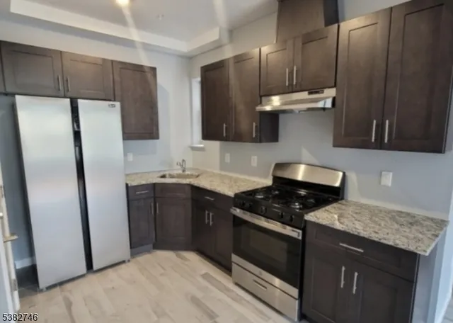 a kitchen with stainless steel appliances a refrigerator a sink and wooden cabinets