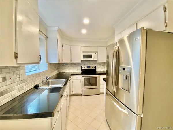 a kitchen with stainless steel appliances granite countertop a refrigerator a stove and a sink