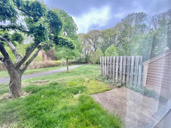 a view of a yard with a tree and wooden fence