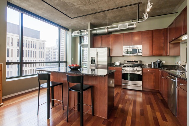 520 South State Street, Unit 501 Chicago, IL 60605 - Photo 11 of 25 a kitchen with stainless steel appliances granite countertop a stove top oven a sink dishwasher a dining table and chairs with wooden floor