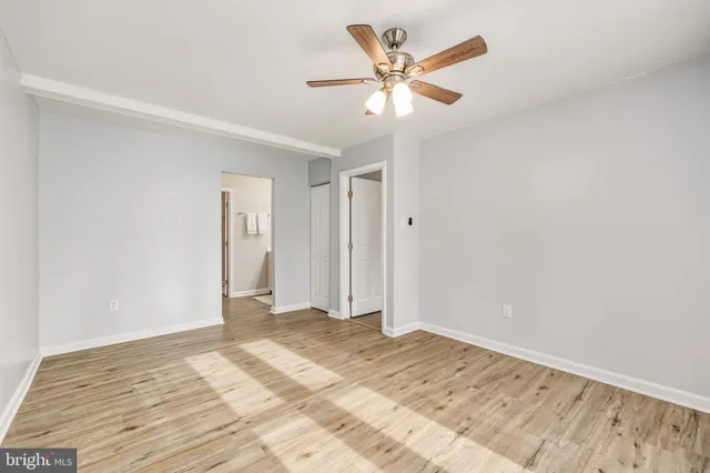 a view of a big room with wooden floor and a chandelier fan