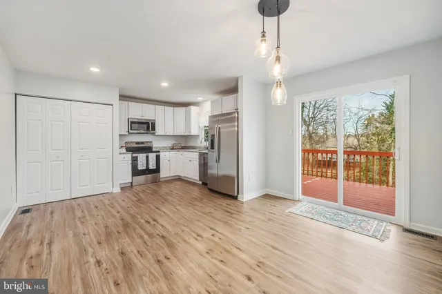 a view of kitchen with stainless steel appliances wooden floor and window