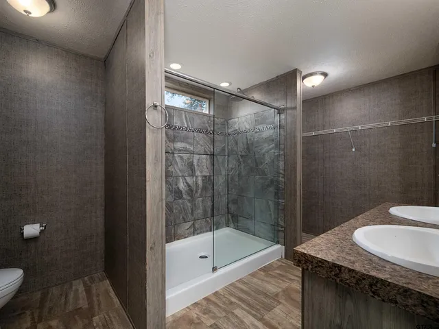 a bathroom with a granite countertop sink a toilet and shower