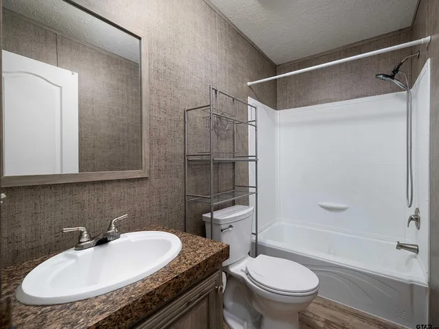 a bathroom with a granite countertop sink toilet and shower