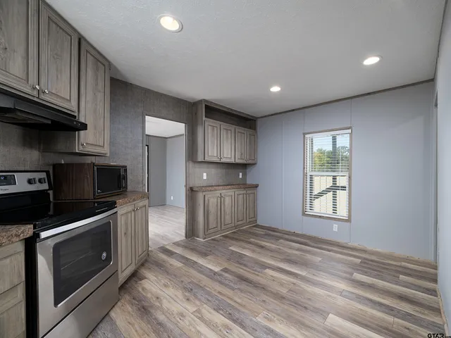 a kitchen with stainless steel appliances granite countertop a stove a sink and a microwave