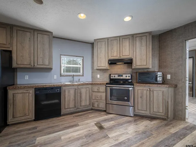 a kitchen with granite countertop a stove cabinets and wooden floor