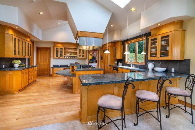 a kitchen with stainless steel appliances granite countertop a table chairs and a wooden cabinets