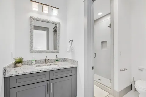 a bathroom with a granite countertop sink vanity mirror and toilet