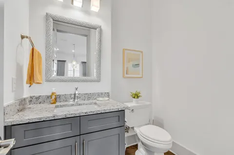 a bathroom with a granite countertop toilet sink and mirror