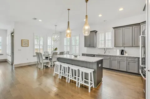 a kitchen with kitchen island granite countertop a sink a center island a stove and a living room view